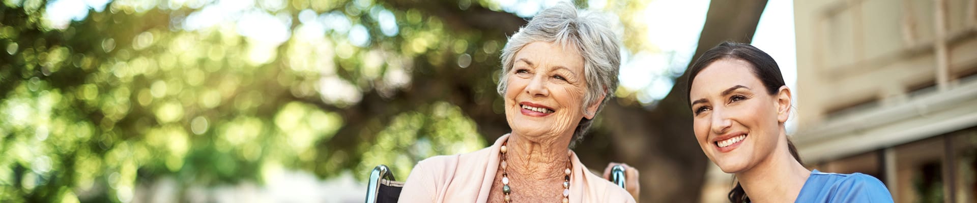 Smiling resident with caregiver in an outdoor setting