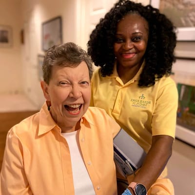 Resident and staff member smiling together in a hallway