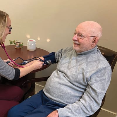 Staff taking a resident's blood pressure in a cozy setting