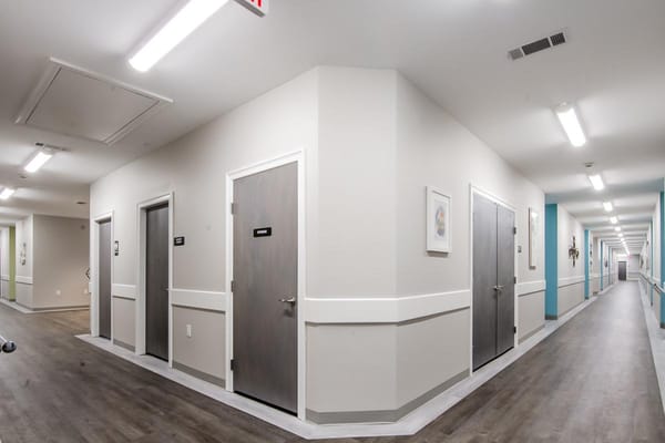 Well-lit hallway with resident rooms and doors