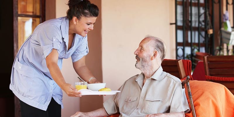 Staff serving meal to resident in a cozy setting