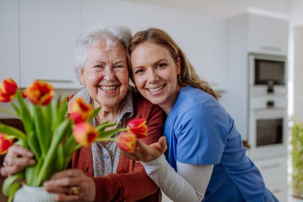 A caregiver and resident smiling together indoors
