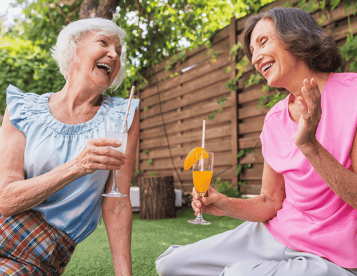 Two seniors enjoying drinks in a garden setting