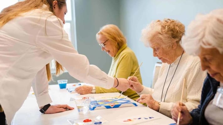 Residents engaging in a painting activity with staff support