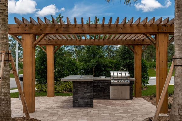 Outdoor grill area with a pergola and stone countertop