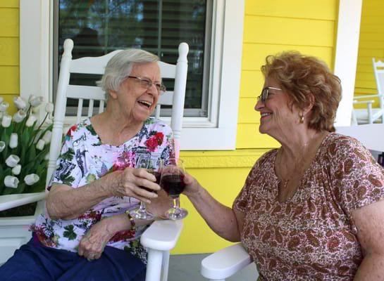 Two senior women enjoying drinks on a porch