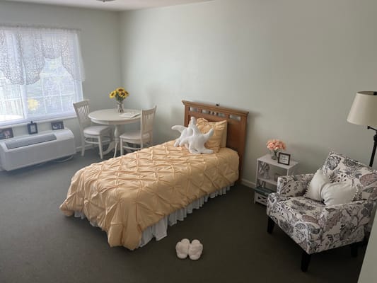 A cozy private resident room with a bed and table