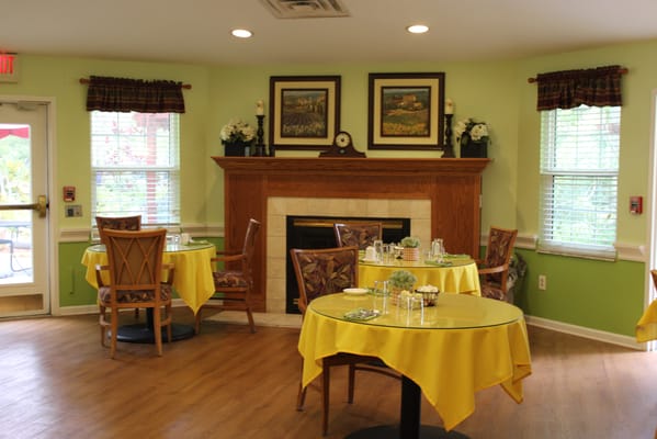 Dining area with yellow tablecloths and a fireplace