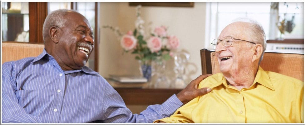 Two elderly men laughing together in a common area