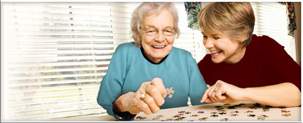 A resident and staff member enjoying a puzzle activity