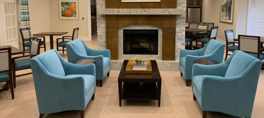 Bright lounge area with teal chairs and a fireplace