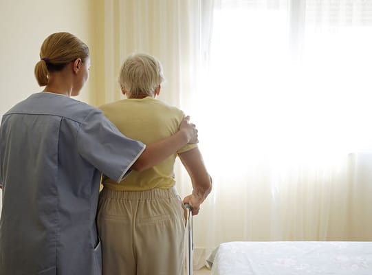 Caregiver assisting an elderly resident in a bright room