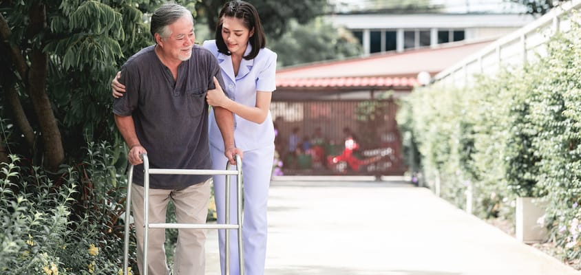 Nurse assisting a resident with mobility outdoors