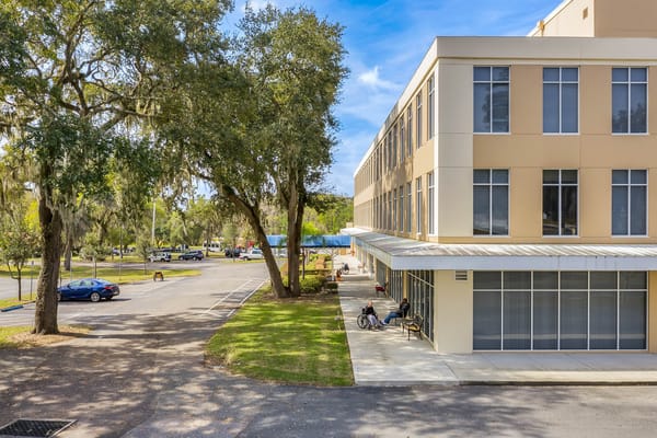 Exterior view of The Grande Senior Living with residents outdoors