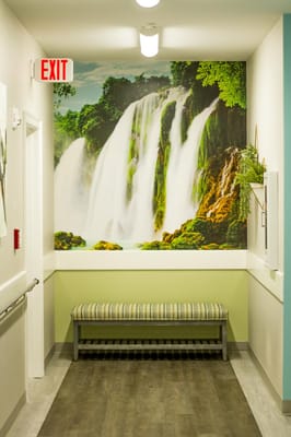 Interior hallway with a waterfall mural and seating