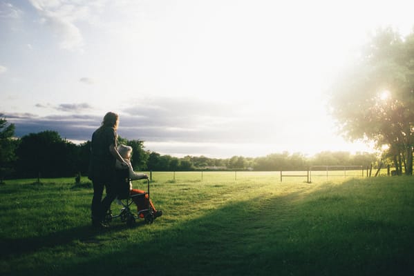 A caregiver walking a resident in a scenic outdoor area