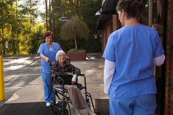 A caregiver assisting a resident in a wheelchair outdoors