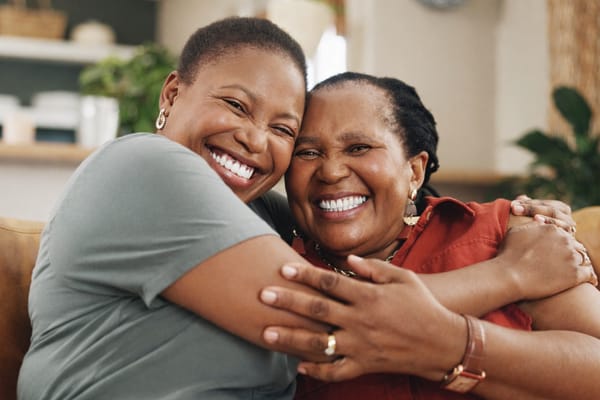 Two women embracing and smiling in a living room