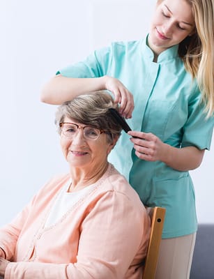 Staff member styling resident's hair in a common area