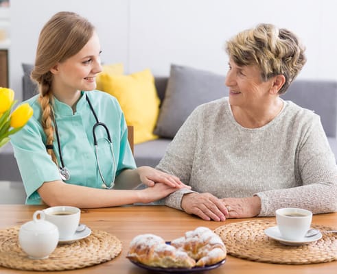 A caregiver interacting with a resident over coffee and pastries