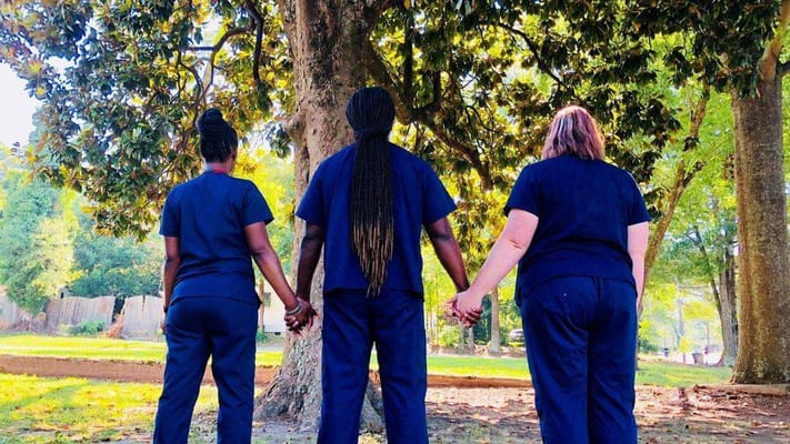 Staff members holding hands under a tree in a garden
