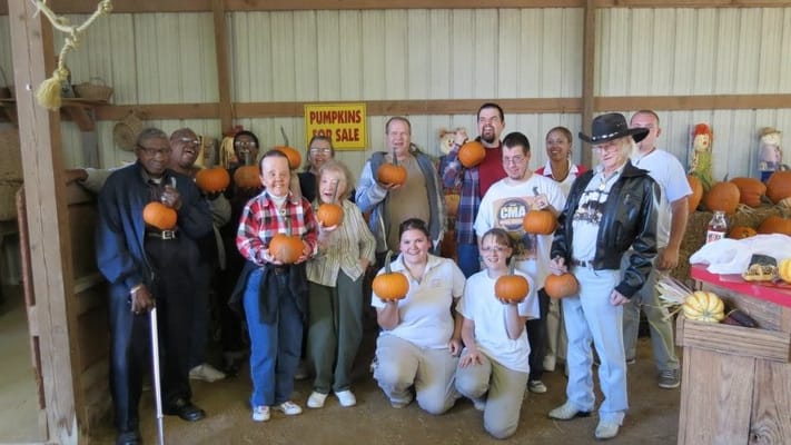 Residents and staff celebrating with pumpkins during an activity