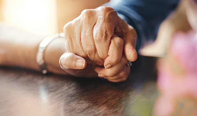 Two hands holding each other on a table