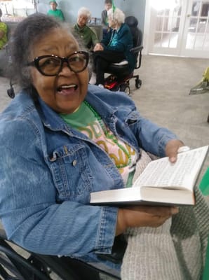 Resident smiling while reading a book in a common area