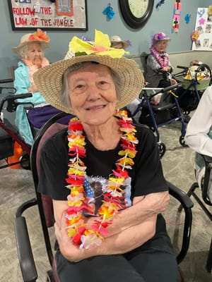 Resident wearing a flower lei and hat in a common area