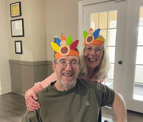 Residents celebrating with seasonal hats in a common area.