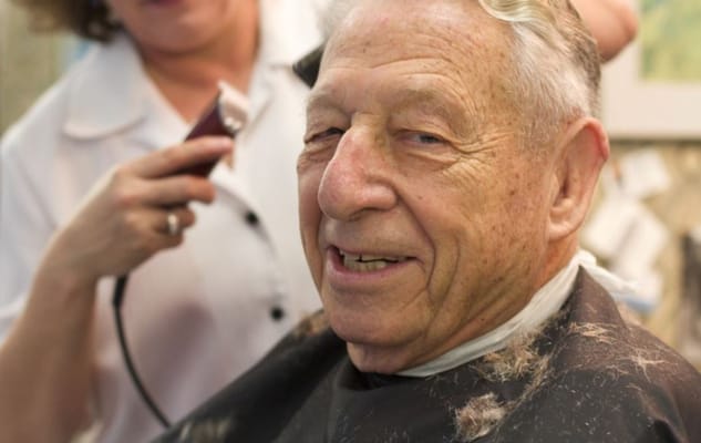 Elderly man receiving a haircut in a salon