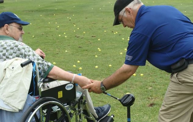 An instructor helping a resident practice golf.