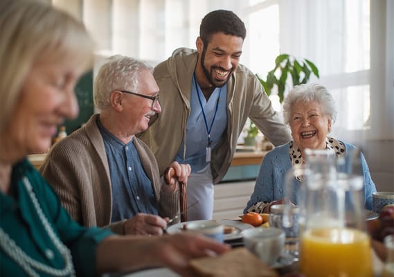 Caregiver interacting with happy residents during meal