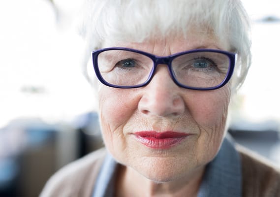 Close-up portrait of a smiling elderly woman with glasses