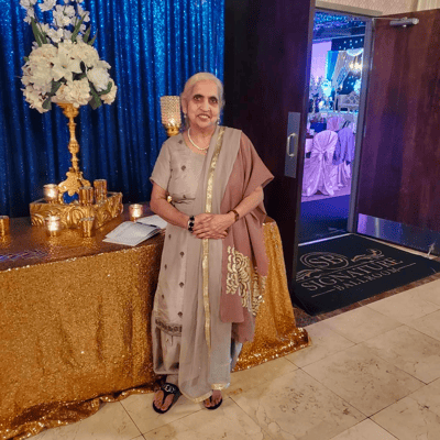 An elderly woman smiling in a decorated interior space