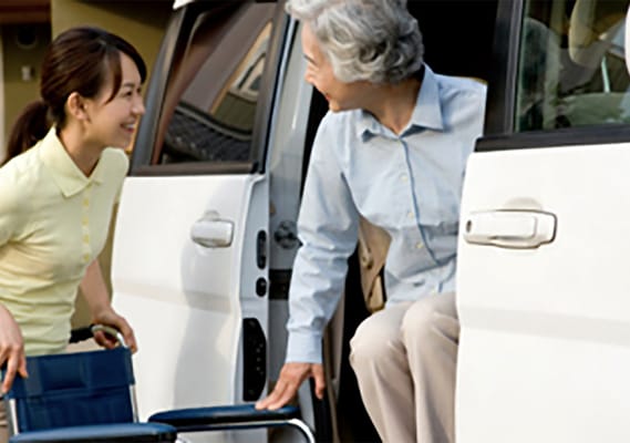 Caregiver assisting an elderly woman from a vehicle
