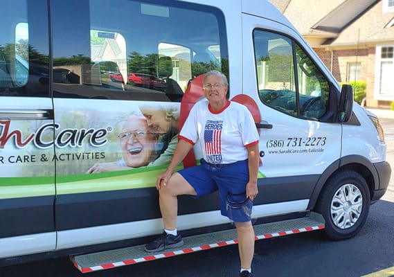 A resident posing next to a facility transport van