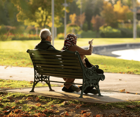 Two seniors sitting on a bench in a park