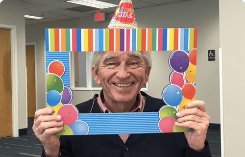 Male resident celebrating with a birthday frame and hat