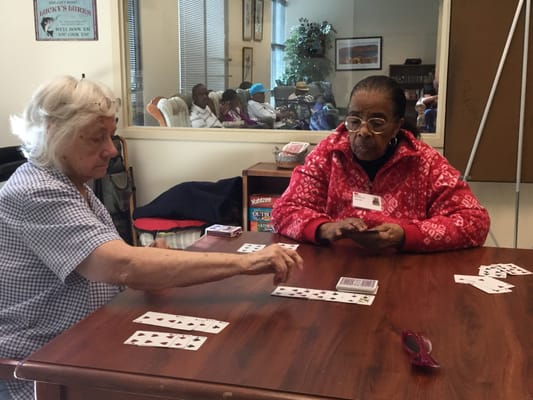 Two residents playing a card game in an activity room