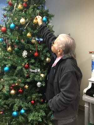 Resident decorating a Christmas tree in the common area