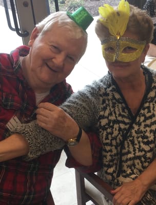 Two residents celebrating with hats and a mask