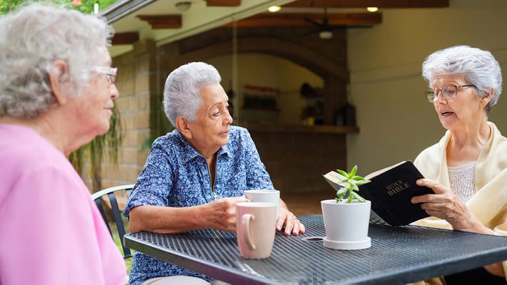Three residents engaged in a conversation outdoors