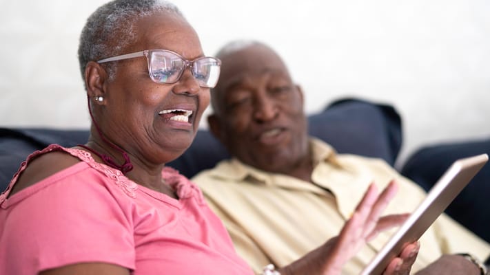 Two seniors enjoying time together with a tablet