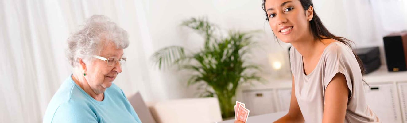 Resident and staff member playing cards indoors