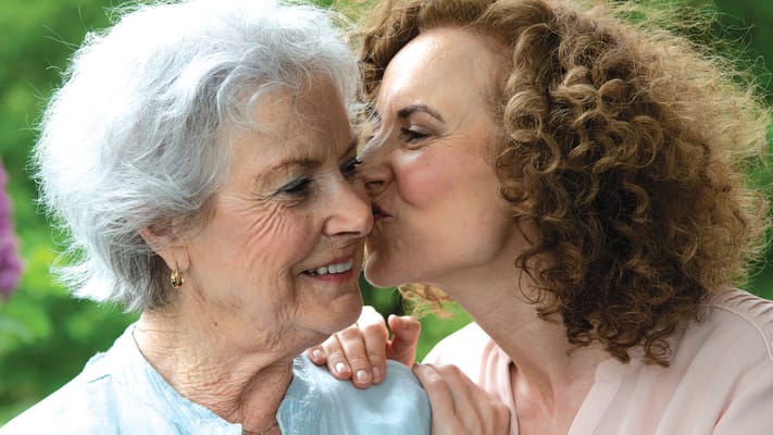 A woman kissing an elderly resident on the cheek