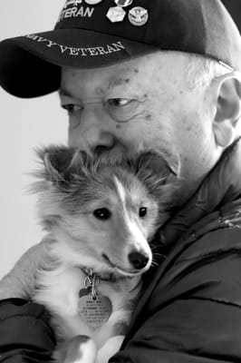 A senior veteran holding a small dog closely