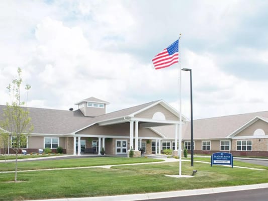 Exterior view of a nursing home facility with flag
