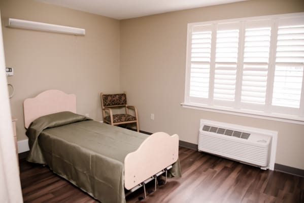 A simple, well-furnished resident room with a bed