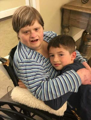 A young boy hugging a woman in a wheelchair